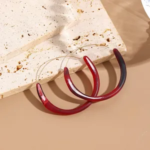 Detailed shot of C-shaped acrylic earrings with gold hoop on travertine stone