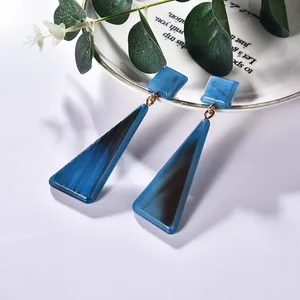 Details von geometrischen blauen Acryl-Ohrhängern mit Marmormuster auf einem Teller