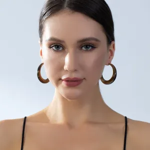 Macro detail of large C-shaped acrylic hoop earrings with brown tortoiseshell texture