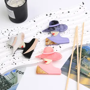 Detail shot of vintage acrylic lady brooches with wide-brimmed hats on a white stand
