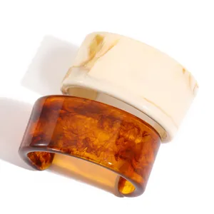 Close-up of translucent amber and cream resin wide cuff bracelets with a polished finish