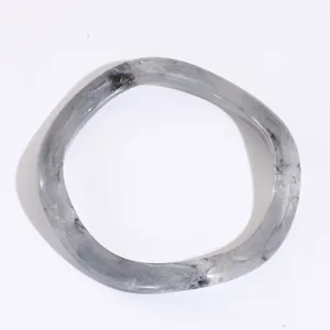 Dettaglio del bracciale in resina con onde irregolari e trama in marmo grigio