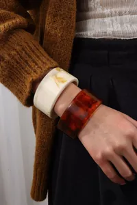 Detail of model wearing translucent amber and marble resin wide cuff bracelets