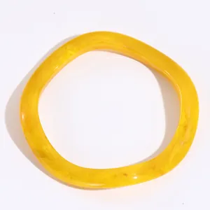 Dettaglio del bracciale irregolare in resina gialla con texture marmorizzata su bianco