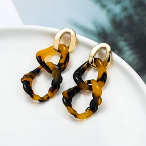 Macro detail of tortoiseshell acrylic rings linked with a polished gold oval metal stud