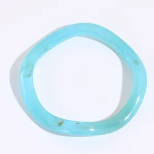 Dettaglio di bracciale in resina azzurro con trama a spirale e venature marroni