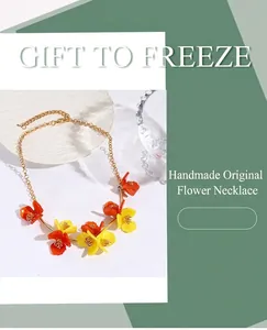 Détail du collier artisanal avec de délicates fleurs en acrylique jaune et orange