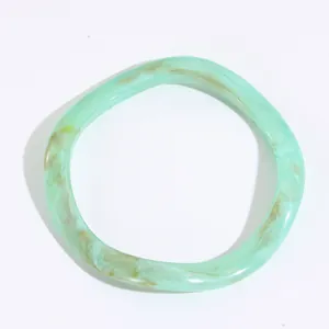 Dettaglio di bracciale rigido in resina a spirale con trama marmorizzata verde e marrone