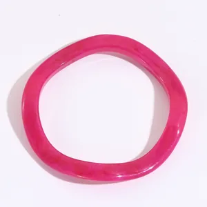 Dettaglio macro di un bracciale in resina rosa a onde con texture marmorizzata e finitura traslucida