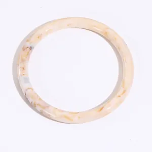 Elegante brazalete de resina vintage con patrón jaspeado ámbar y crema sobre fondo blanco