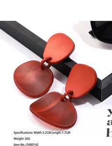 Macro detail of terracotta geometric acrylic earrings with matte wood-like texture