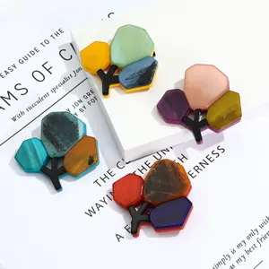 Detail of artistic tree brooches with colorful acrylic slices on white background