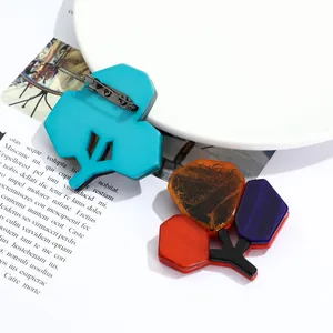 Artistic acrylic branch brooch with colorful geometric patterns on a white ceramic plate