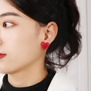 Orecchini a cuore in acrilico rosso su modella per un look estivo alla moda e vivace