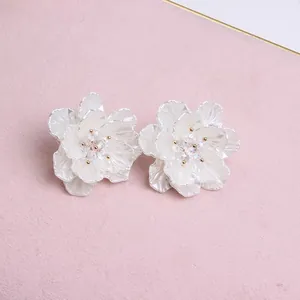 Macro detail of acrylic flower earrings with pearl finish petals and crystal centers