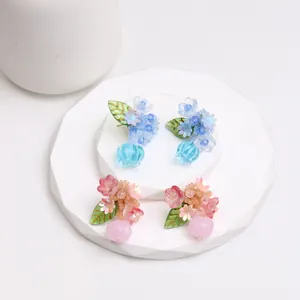 Detail view of acrylic flower stud earrings in translucent blue and pink colors