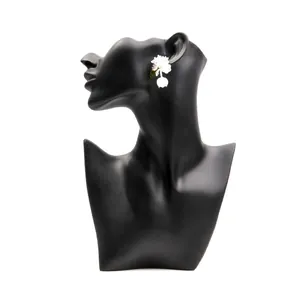 Detailed view of elegant white floral stud earrings featuring a delicate pearl pendant