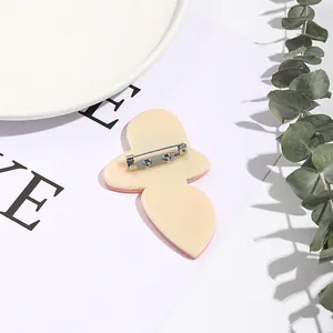 Detailed back view of acrylic brooch showing secure silver metal safety pin and screw fasteners
