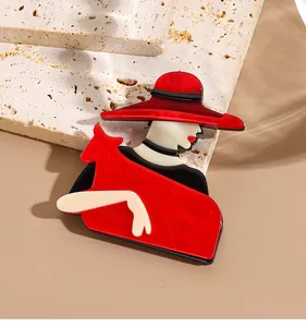 Détail macro d'une broche en acrylique avec une femme élégante au chapeau rouge sur pierre