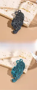 Detail view of cheetah brooches in grey and teal leopard patterns on travertine