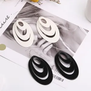 Macro shot of tiered oval acrylic hoop earrings in cream white and glossy black