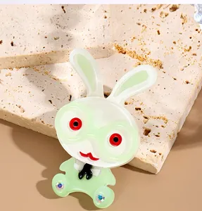 Detailed close-up of cartoon rabbit brooch with green glasses and sparkly rhinestones