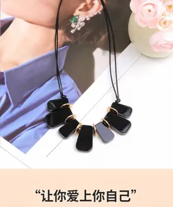 Détail du collier moderne en acrylique noir avec pendentifs géométriques dorés