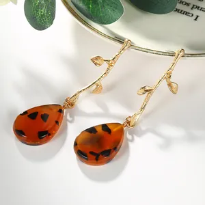 Boucles d'oreilles branche dorée avec goutte d'eau en acrylique ambré de style naturel
