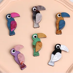 Detailansicht von Vogel-Broschen mit buntem Marmormuster auf einem rosa Tablett