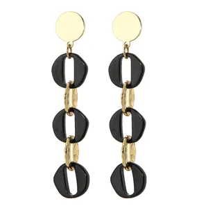 Détail de boucles d'oreilles pendantes avec disques dorés et chaînes à maillons noirs