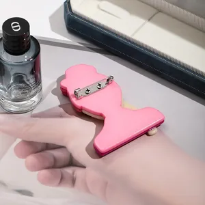 Pink acrylic girl figure brooch shown on hand with elegant luxury product accessories