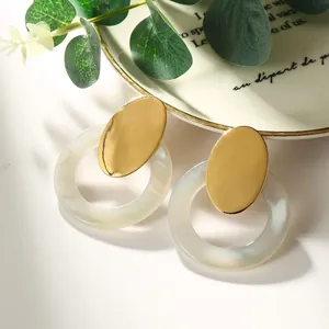 Detail of acetate resin earrings with golden metal studs and marble texture hoops