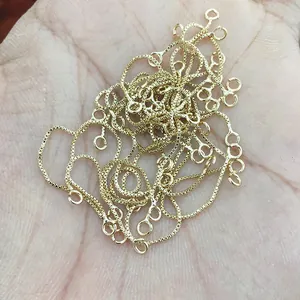 Mano sujetando hilos de pendientes de cadena box de oro de 14k y accesorios de DIY