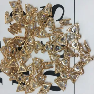Macro detail of gold triangular alloy pendants with zircon inlay for jewelry making