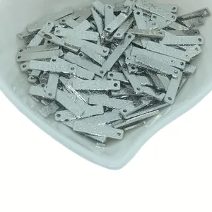 Détail macro de pendentifs rectangulaires en métal argenté brossé avec deux trous de lien