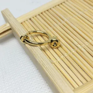 Detail view of gold-plated non-pierced spring earring converter on a textured background