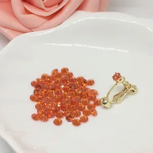 Detalle de pendiente de clip dorado con circón naranja en un plato de cerámica