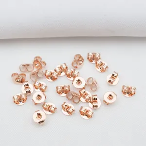 Vista macro de cierres de pendientes redondos y de mariposa en oro rosa de 14k