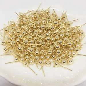 Clous d'oreilles sphériques plaqués or avec boucles de suspension sur un plat en céramique blanc