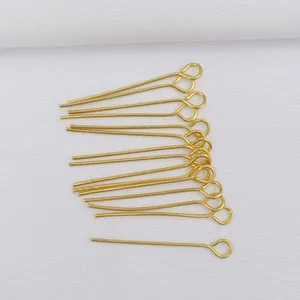 Detailed view of 14k gold-plated eye pins on white fabric for DIY jewelry making