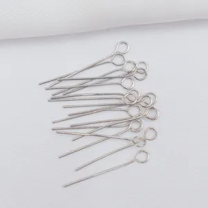 Macro shot of silver metal eye pins for DIY jewelry making on white textured fabric