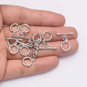 Nahaufnahme von silbernen OT-Knebelverschlüssen für Schmuck in der Hand gehalten