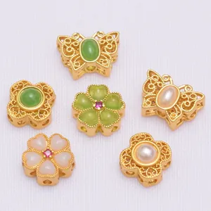 Detailed view of six gold-plated floral and butterfly beads with pearls and green gemstones