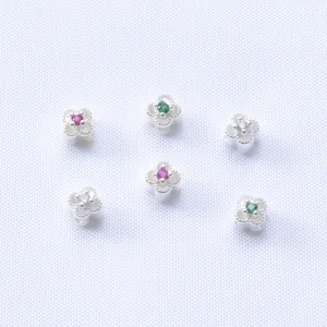 Detalle macro de cuentas de trébol chapadas en oro de 14K con circonitas de colores