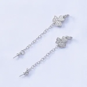 Elegant silver clover drop earrings with sparkling cubic zirconia on a purple fabric background