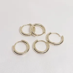 Classic 14k gold-filled round hoop earrings set on white fabric texture