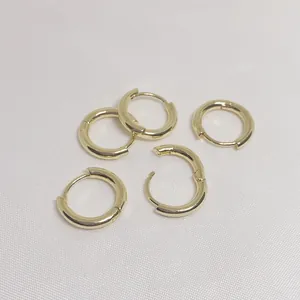 Set of five polished 14k gold-filled round hoop earrings on white silk fabric background