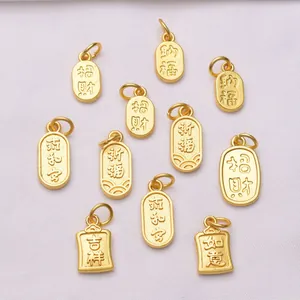 Macro de 10 pendentifs lotus dorés avec caractères chinois sur un tissu blanc texturé