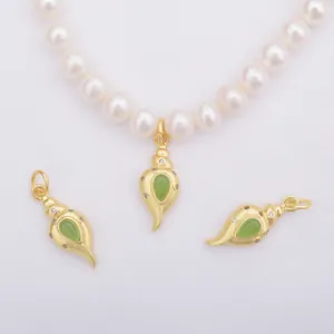 Macro detail of gold conch pendants with green gemstones on a pearl necklace