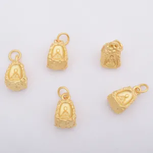 Vue macro de cinq pendentifs Bouddha dorés avec texture mate sur tissu blanc